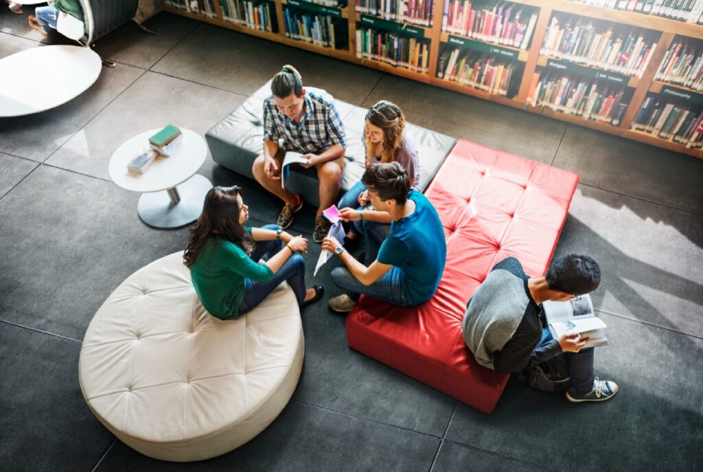 Cuatro chicos reunidos en la biblioteca o una tienda de libros, reflejando comunidad
