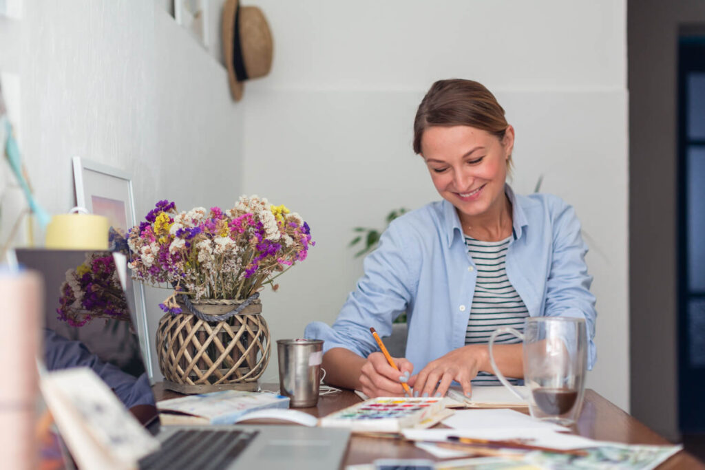 Mujer con libros, calculadora y sonriendo por ser una escritora emprendedora